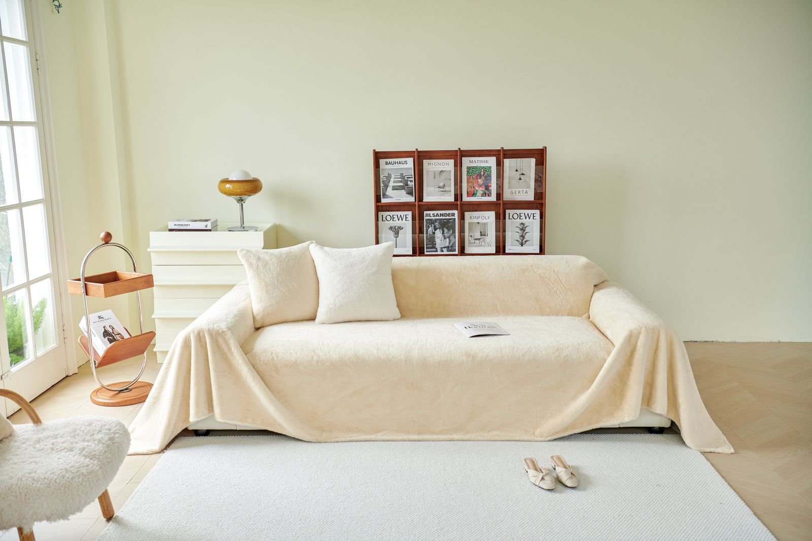 A bright living room with a cream throw draped over the sofa and simple, minimal decor